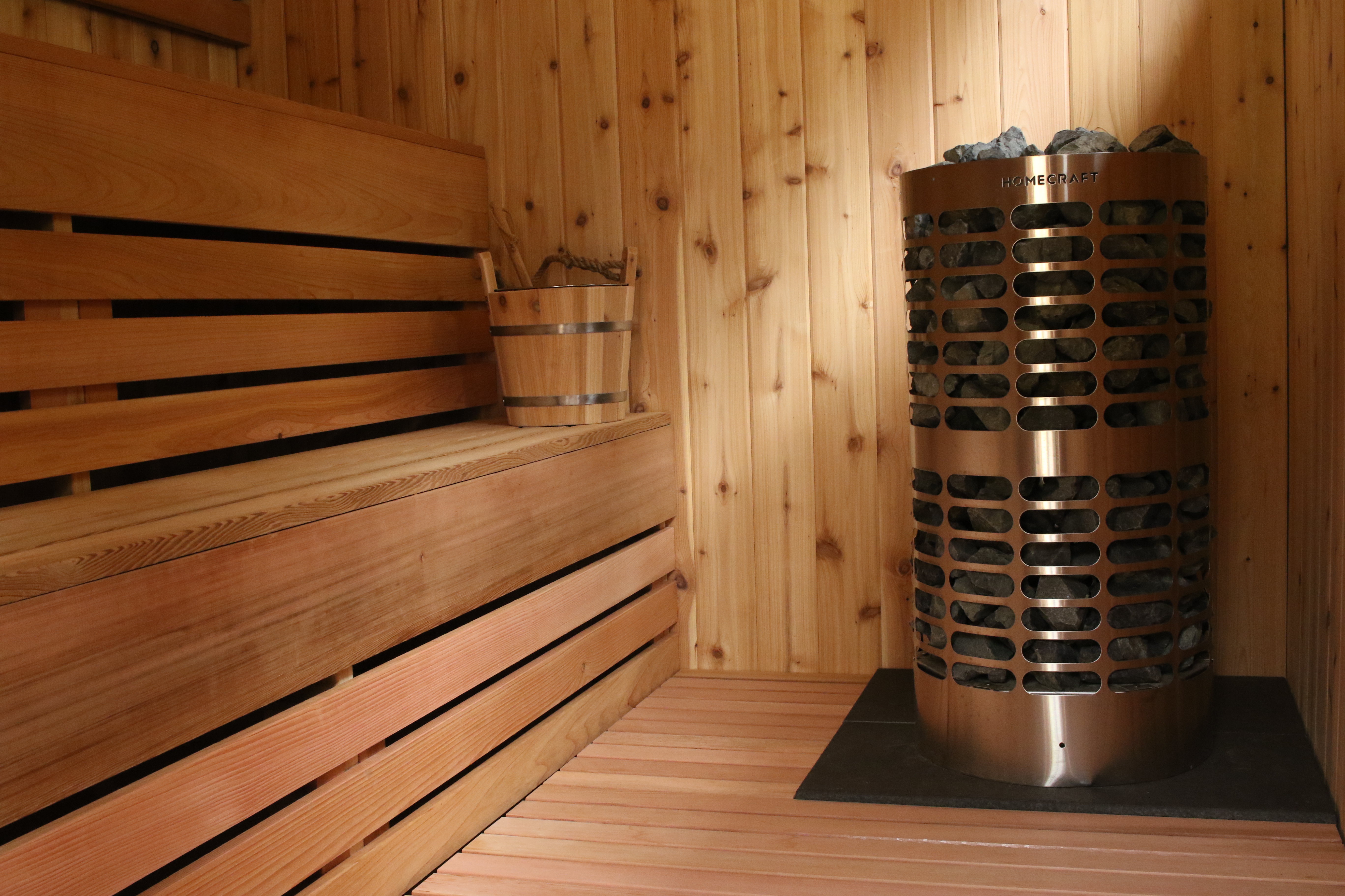 Stone heater and cedar benches in a SCHÖN sauna